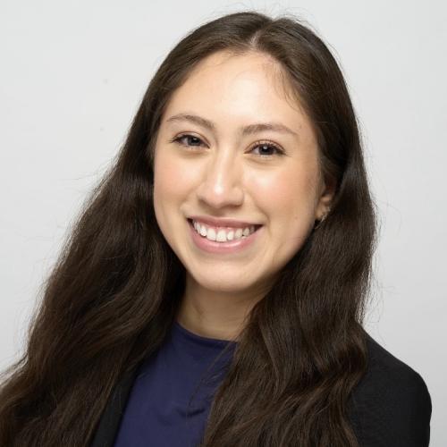 Headshot of Diana Garcia. She wears a dark blue shirt and stands in front of a white background.